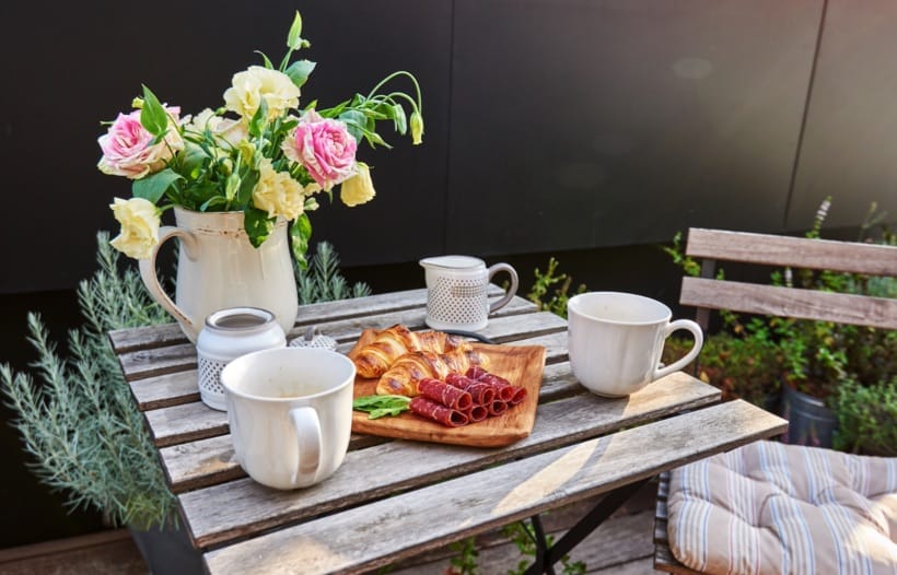 Outdoor food, cups and flowers on table