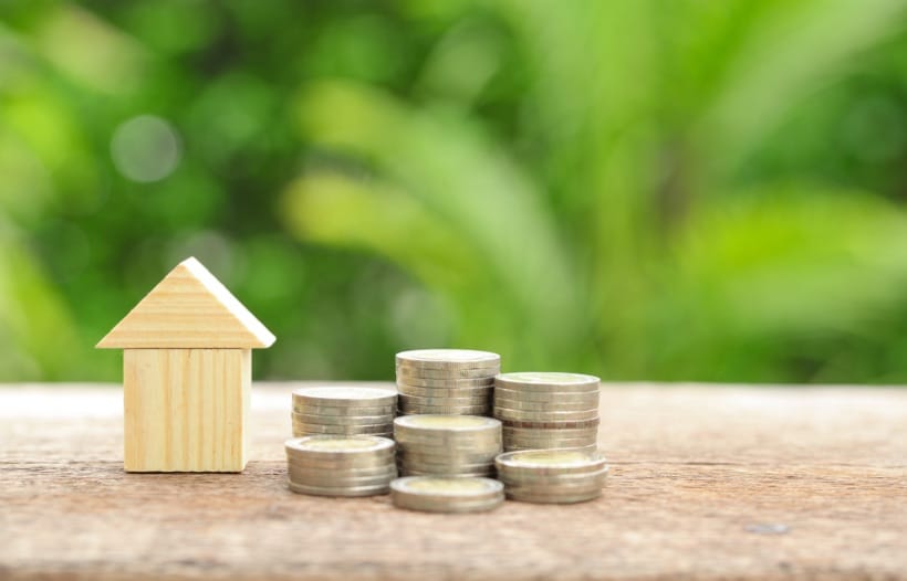 House block and piles of coins on table