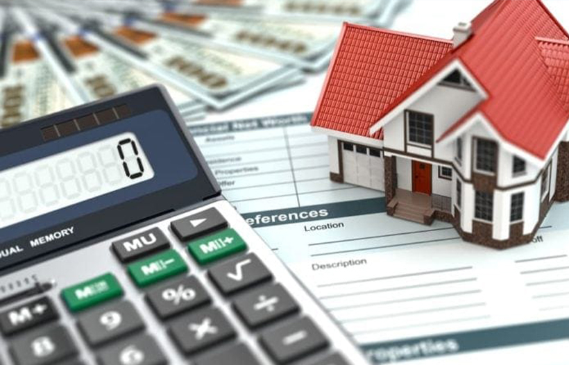 House model and calculator on top of paperwork