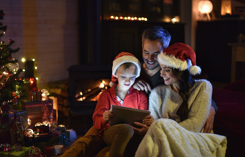 Family looking at tablet device near Christmas tree