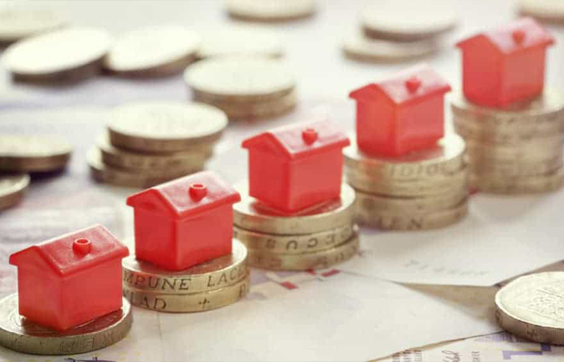 House models positioned on piles of coins