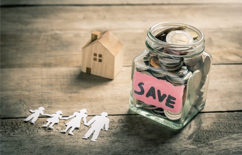 Save jar with money, family cardboard cutout and wooden house on floor
