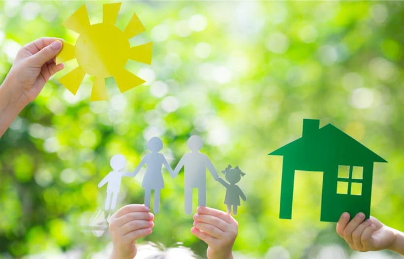 Family holding cardboard cut-outs of the Sun, family and house